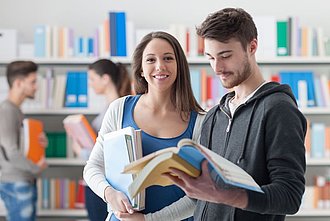 Junger Mann und junge Frau stehen in Bibliothek
